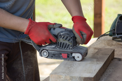 man grinds a board with sander