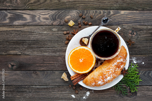 Continental breakfast - cup of hot coffee, croissant and orange. Tasty food on rustic wooden background. Top view, place for text.