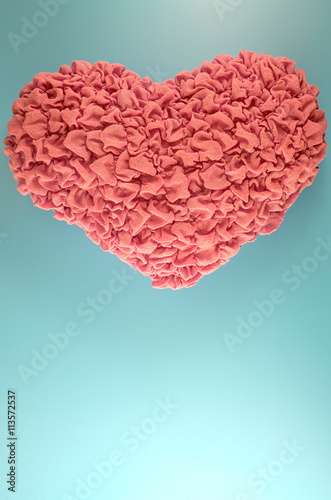 Pink heart pillow on blue background.