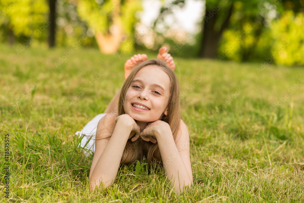 Portrait of a beautiful young girl lying on the grass outdoors in summer Portrait of a beautiful young girl lying on the grass outdoors in summer