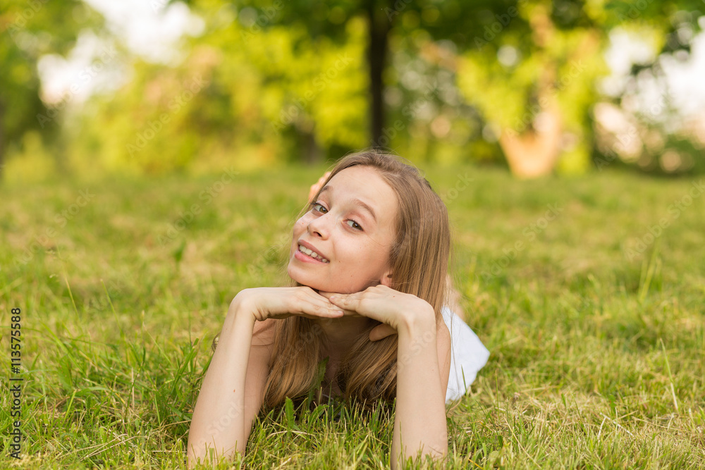 Portrait of a beautiful young girl lying on the grass outdoors in summer Portrait of a beautiful young girl lying on the grass outdoors in summer
