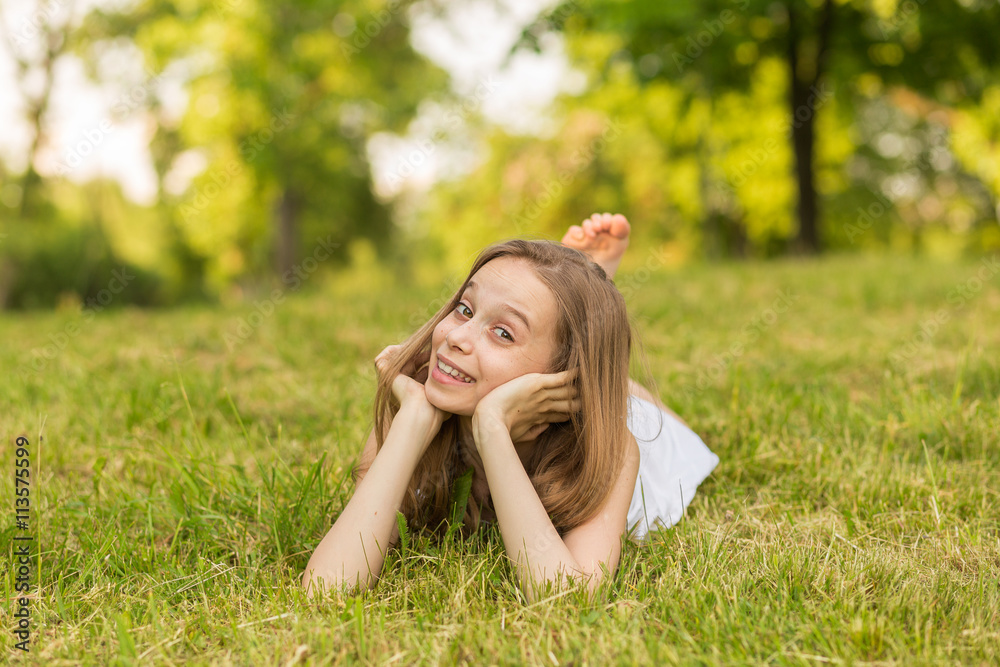 Portrait of a beautiful young girl lying on the grass outdoors in summer Portrait of a beautiful young girl lying on the grass outdoors in summer