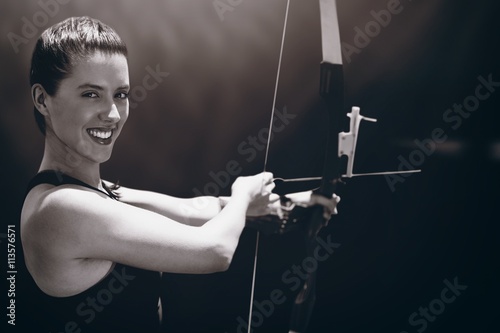 Image of portrait of sportswoman is doing archery