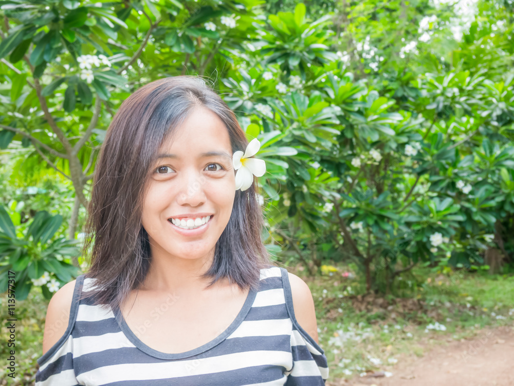 Close up portrait of a beautiful asian woman smiling outdoors. Enjoy Nature. Healthy Smiling Girl in white plumeria on the plumeria tree. Close up portrait of a beautiful asian woman smiling outdoors. Enjoy Nature. Healthy Smiling Girl in white plumeria on the plumeria tree.