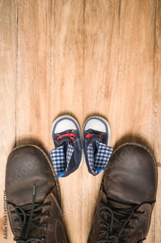 Daddy's boots and baby's sneakers, on wood background, fathers d