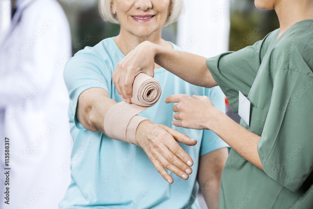 Nurse Putting Crepe Bandage On Patient's Hand At Rehab Center