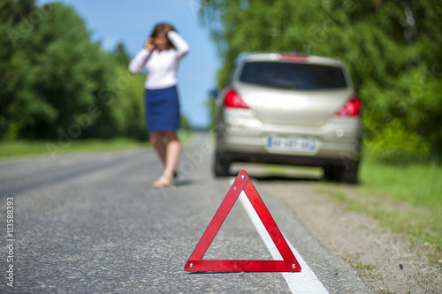 Red triangle sign and broken car on the roadside