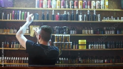 vape shop seller show e-cigarettes to buyer and exhaling smoke