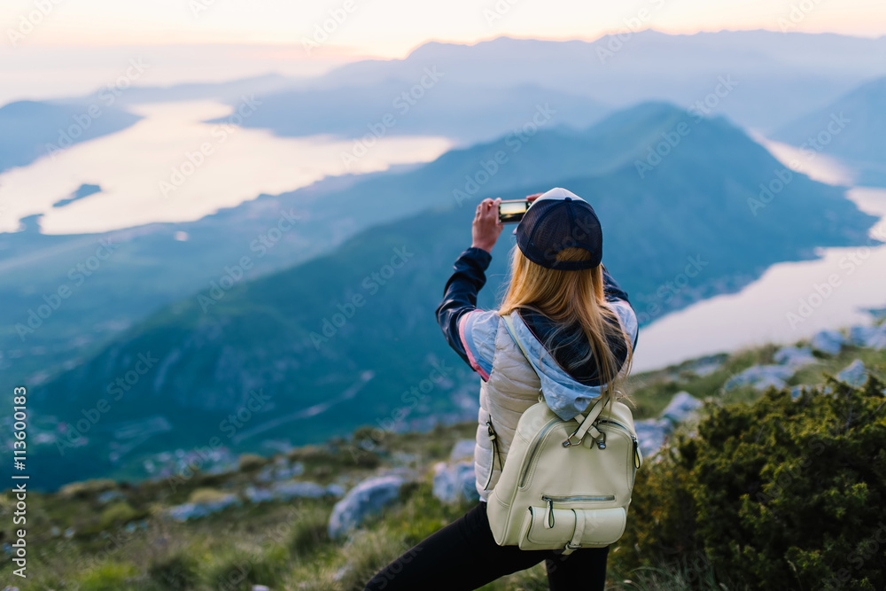 Φωτογραφία Shot of a young woman taking pictures from the top of a mountain