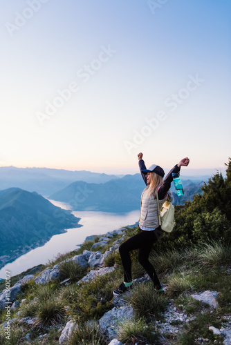 Young happy tourist on top of a mountain enjoying the view of sunset 