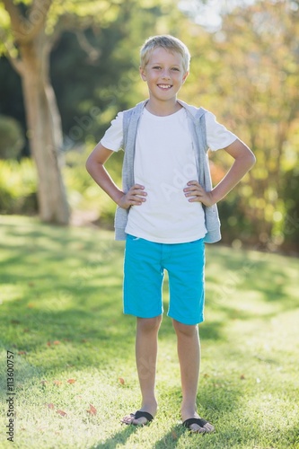 Portrait of smiling boy standing with hand on hip in park