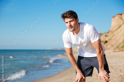 Man in white t-shirt and shorts standing on beach