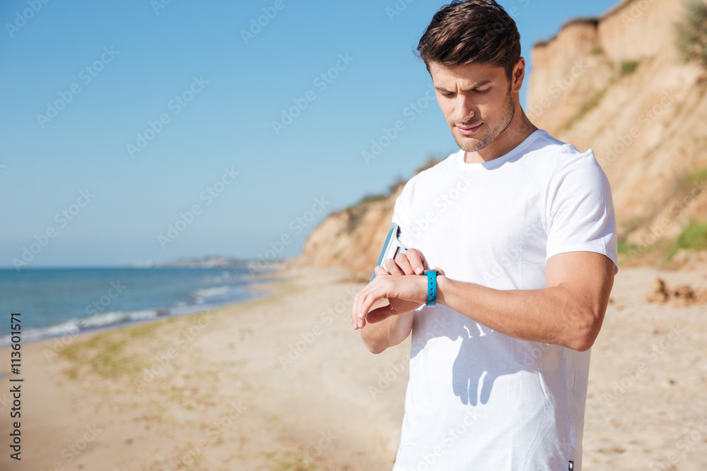 Sportsman using activity tracker on the beach Sportsman using activity tracker on the beach