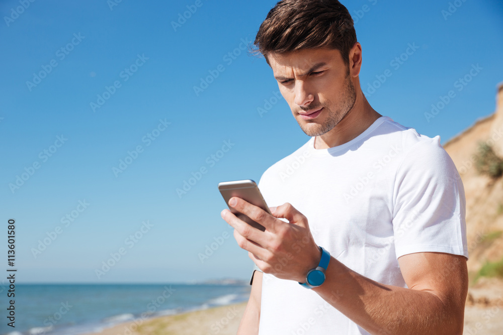 Sportsman using fitness tracker and smartphone outdoors