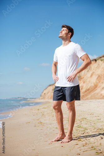 Relaxed man standing barefoot on the beach