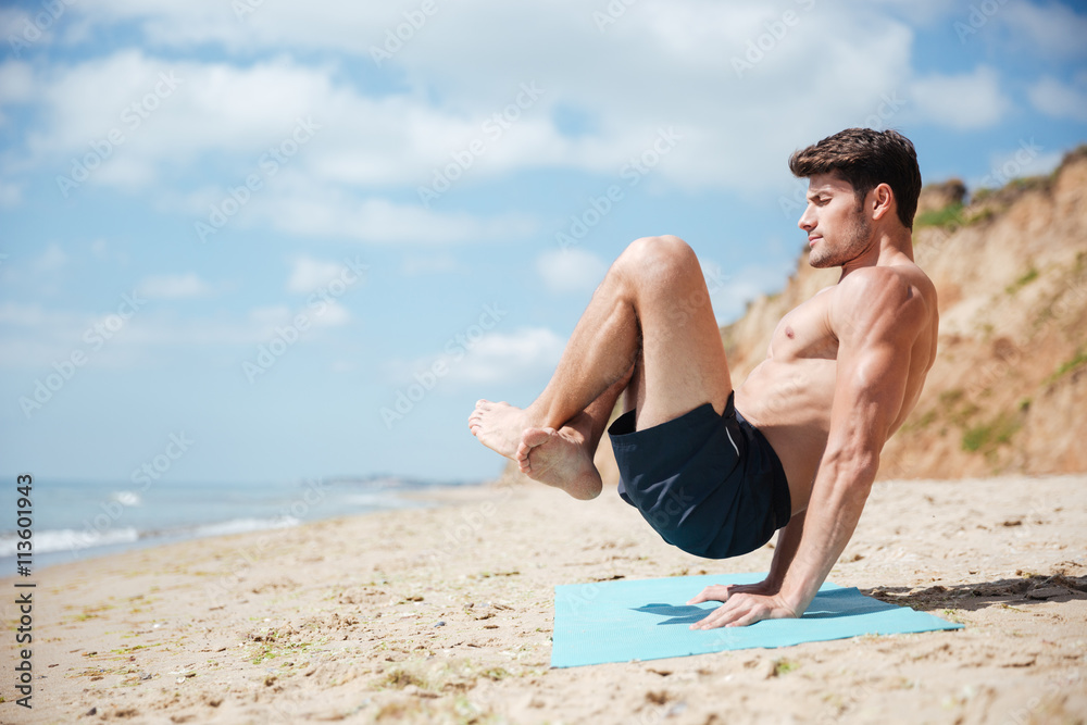 Man with eyes closed practicing yoga on the beach