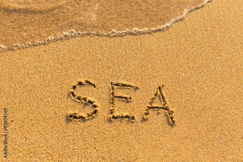 Sea - word drawn on the sand beach with the soft wave. © De Visu