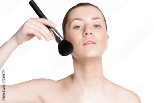 beautiful woman with clear skin holds cosmetic brush