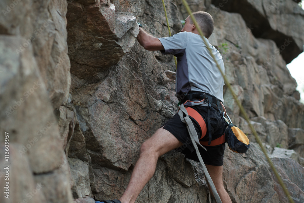 Male rock climber clings to a cliff Male rock climber clings to a cliff