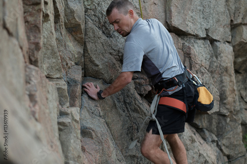 Male rock climber clings to a cliff