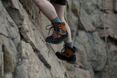 Legs of male rock climber clings to a cliff