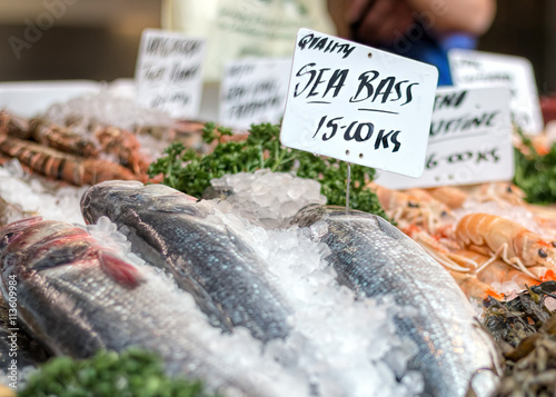 Картината върху платно Fresh sea bass and seafood at market counter.