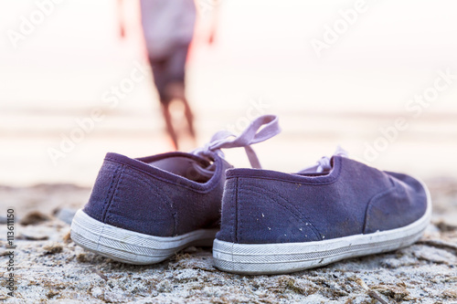 two sneakers at the beach with running boy in background