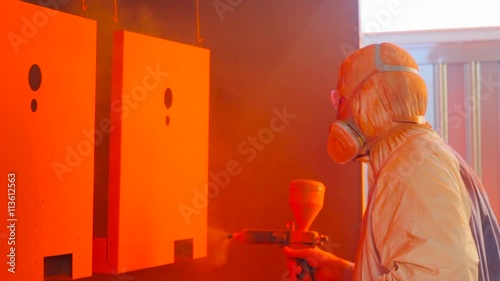 man painting semi finished metal parts in a factory photo