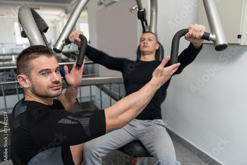 Man Train Chest On Machine With Personal Trainer