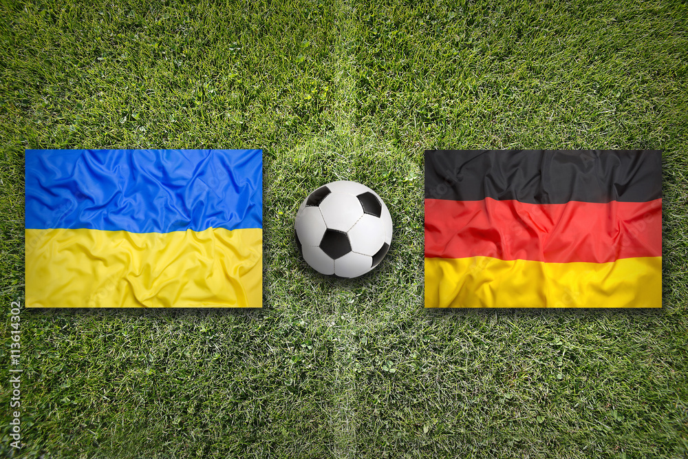 Fototapeta premium Ukraine vs. Germany flags on soccer field