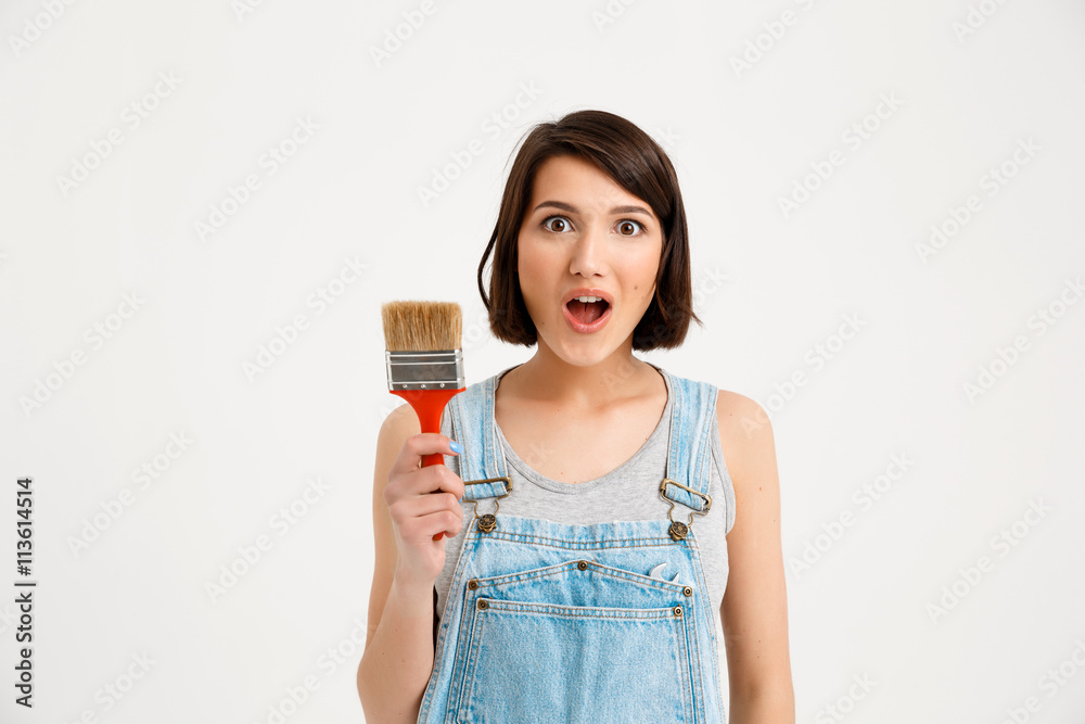 portrait of young pretty girl, looking surprised, holding pain portrait of young pretty girl, looking surprised, holding pain