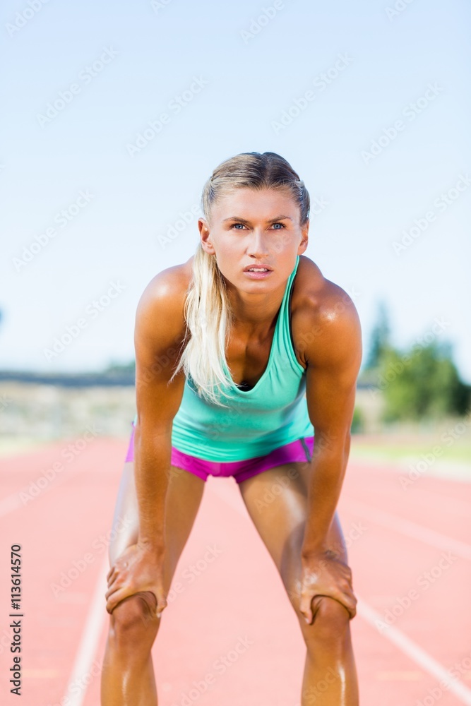 Tired female athlete standing on running track Tired female athlete standing on running track