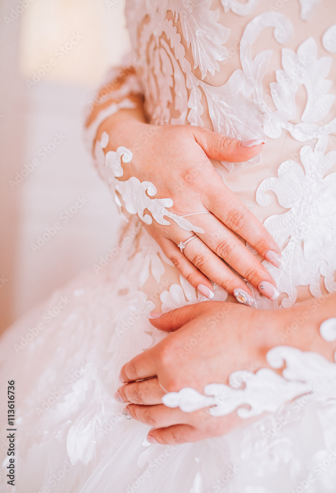 Bride sitting in a beautiful white dress, hands with a wedding ring with a jewel of a close-up. Morning of the bride. Wedding day. Bride sitting in a beautiful white dress, hands with a wedding ring with a jewel of a close-up. Morning of the bride. Wedding day.