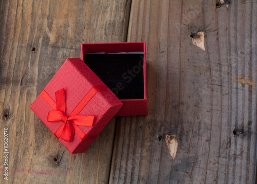 Red color gift box with bow on wooden background