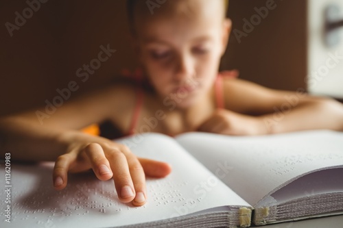 Fototapet Little girl using his right hand to read braille