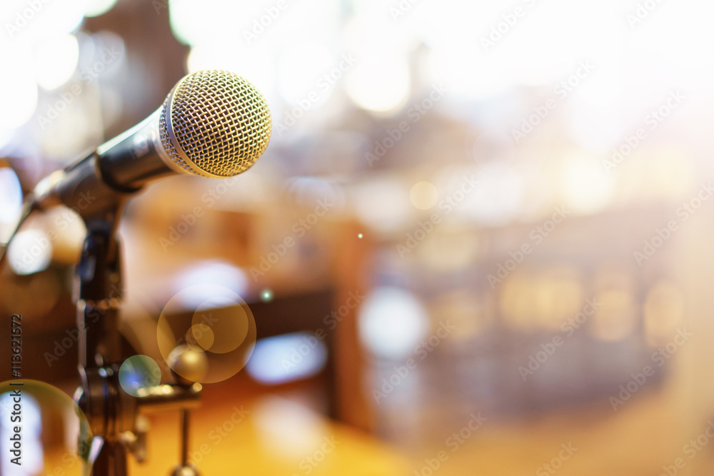 Naklejka premium Mikrofon nad Abstrakcjonistyczną zamazaną fotografią sala konferencyjna lub
