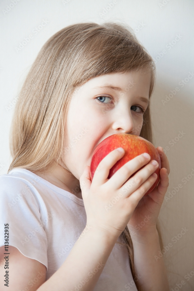 Smiling little girl eating a big red apple Smiling little girl eating a big red apple