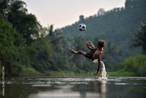 Fototapeta Naklejka Na Ścianę i Meble -  Boy playing football with kicking soccer ball