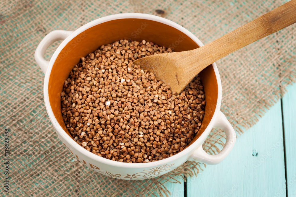 Buckwheat groats in a bowl and wooden scoop Buckwheat groats in a bowl and wooden scoop