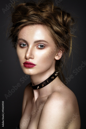 Woman fashion portrait on grey background. Young lady posing close up in studio with red lips and leather necklace on neck.