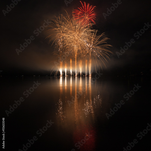 Colorful fireworks with reflection on lake.