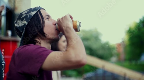 Young longboardist man drinking mineral water in the city