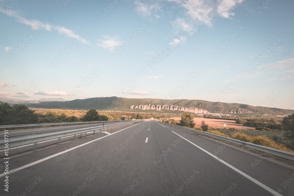 Fototapeta premium Paved two lane road crossing mountains and forest. Panoramic view from car mounted camera. Summer adventure and roadtrip in the French Alps. Toned image, vintage style.