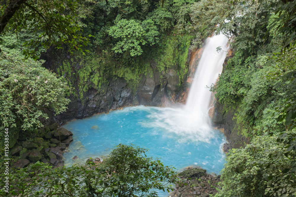 Naklejka premium Wodospad w dżungli z błękitną wodą / krajobraz