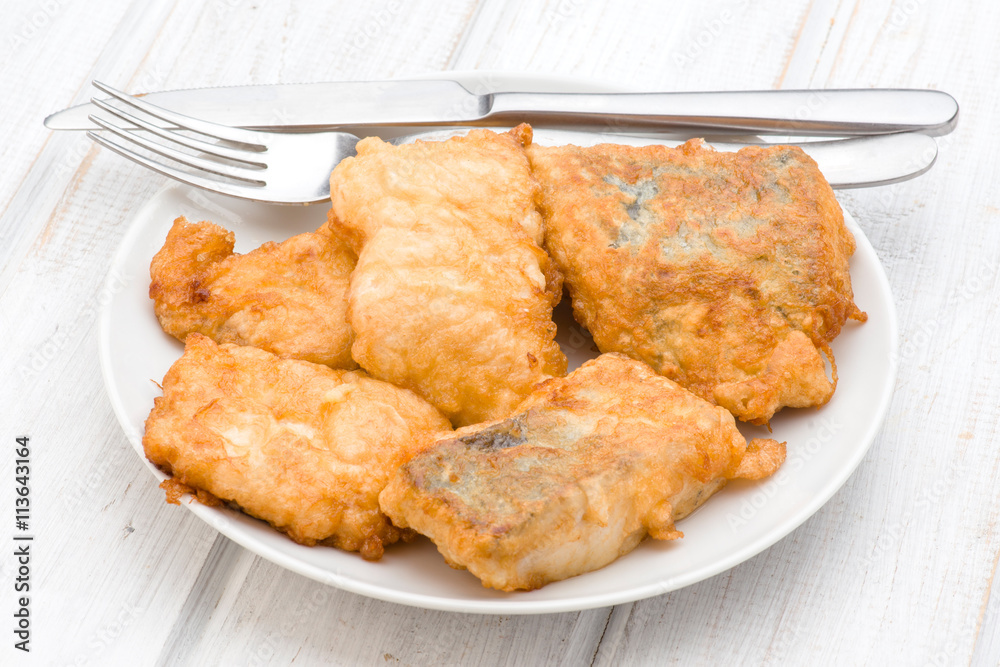 pieces of fried hake plate with cutlery on wooden pieces of fried hake plate with cutlery on wooden