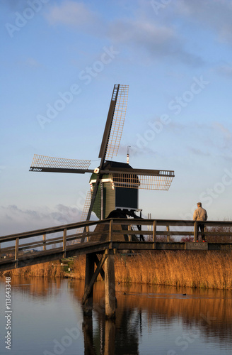 Man looking at the 'Achterlandse molen' from a bridge acroos the 'Ammersche Boezem' 