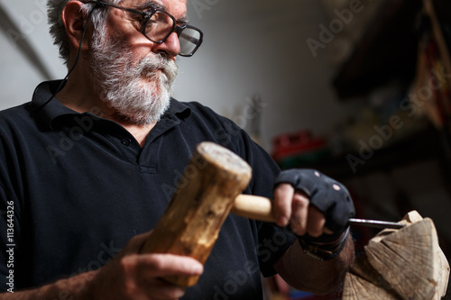 Senior sculptor working on his sculpture in his workshop.