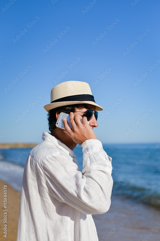 Happy young man using smart phone, outdoors beach background