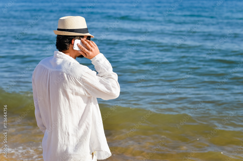 Back view of person using smart phone, outdoors beach background
