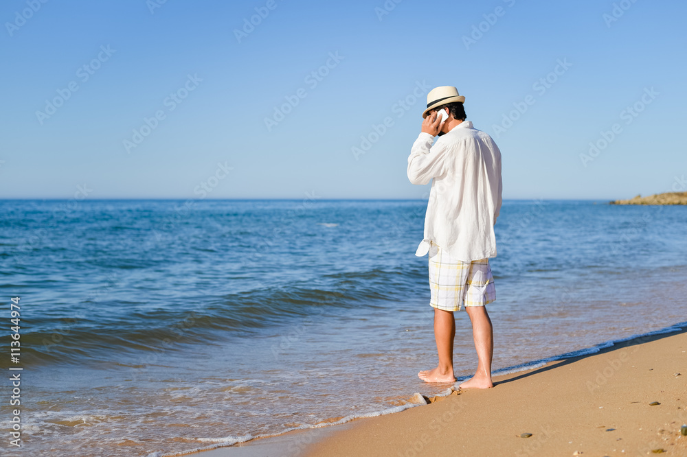 Busy man calling by mobile phone on sandy beach outdoors